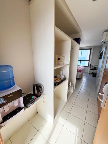 a small kitchen with white cabinets and a white tile floor at Ponta Negra Flats Confort Accommodations Vista para o Mar in Natal