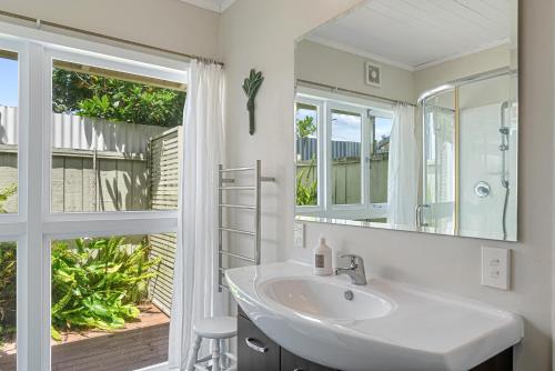 a bathroom with a sink and a mirror at Tutere Treasure - Waikanae Holiday Home in Waikanae