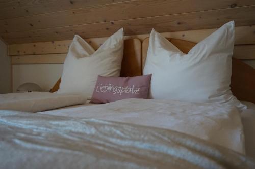 a white bed with white pillows and a purple pillow at Seminar- und Erlebnishof Das schwarze Schaf in Bad Gams