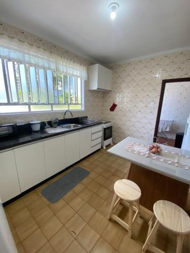 a kitchen with white cabinets and a table and chairs at RCM Vilas - Casa Confortável 02 in Joinville