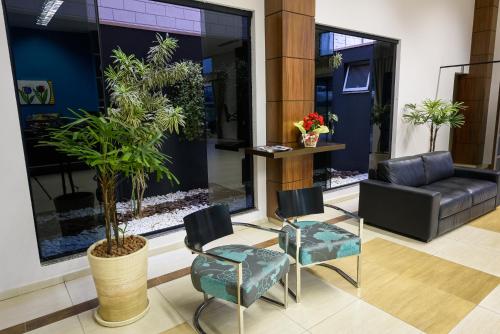 a lobby with a couch and chairs and a plant at Prisma Plaza Hotel in Taubaté