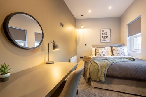 a bedroom with a bed and a table with a mirror at Harland House in Belfast