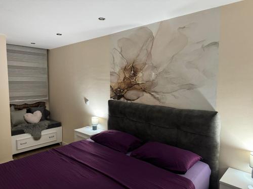 Un dormitorio con una cama morada y una pintura en la pared. en Apartman Jaman - Novi Pazar, en Novi Pazar
