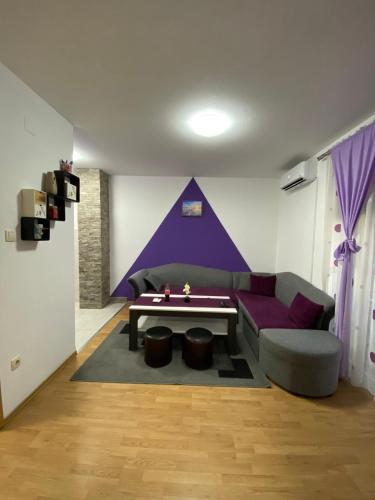 ein Wohnzimmer mit einem lila Sofa und einem Tisch in der Unterkunft Apartman Stanić in Bosanska Gradiška