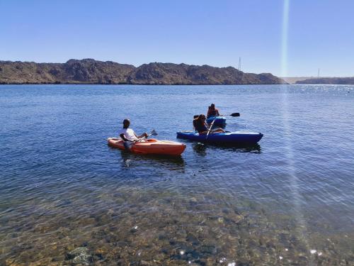 three people are in kayaks on a lake at Miskaa Nubian House in Naj‘ Tinjār