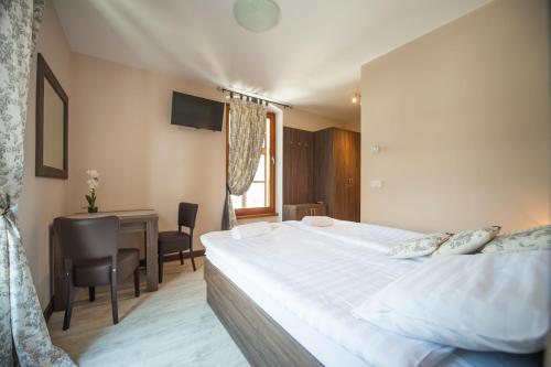 a bedroom with a large white bed and a desk at Hotel Pri mostu in Dolenjske Toplice