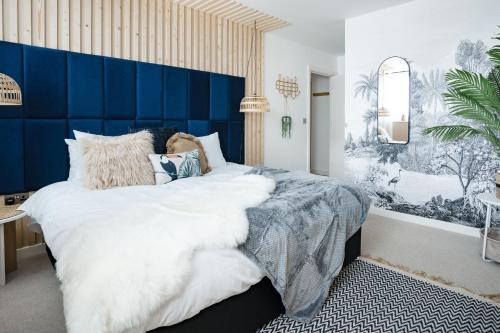 a bedroom with a large bed with a blue headboard at 2-bed near Gloucester & Cotswolds - 2x parking, desk, fibre, arcade in Gloucester