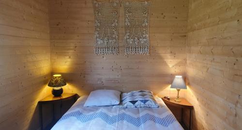 Cama en habitación de madera con 2 lámparas en Pavillon de la biche, en Commensacq