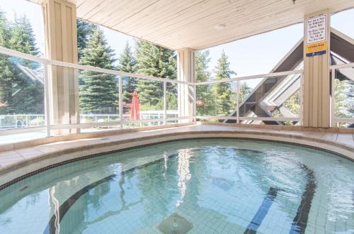 an indoor swimming pool with a large window at Wildwood Lodge by Outpost Whistler in Whistler