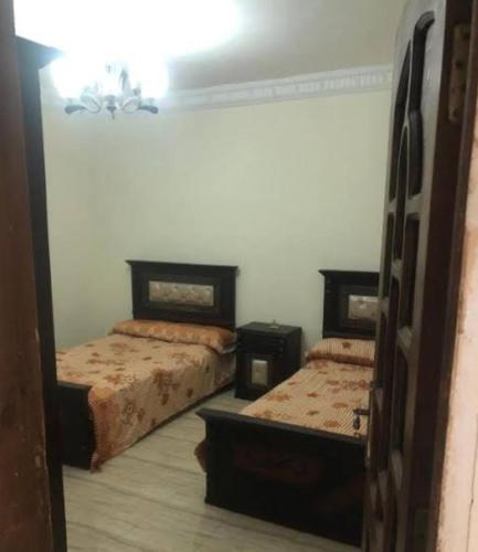 1 dormitorio con 2 camas y espejo en شقة عيسى en Dumyāţ al Jadīdah