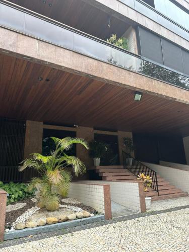 a building with a staircase and palm trees in front of it at Ed Vila de Ofir 200m da Praia in Rio de Janeiro