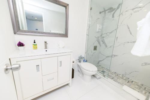 uma casa de banho branca com um chuveiro e um WC. em SeaStays Apartments em Miami Beach