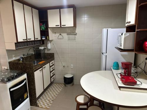 a small kitchen with a table and a refrigerator at Ed Vila de Ofir 200m da Praia in Rio de Janeiro
