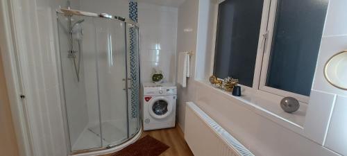 een badkamer met een douche en een wasmachine bij OLIVE TREE - 2 Master bedroom (sleeps 6) in Blackpool