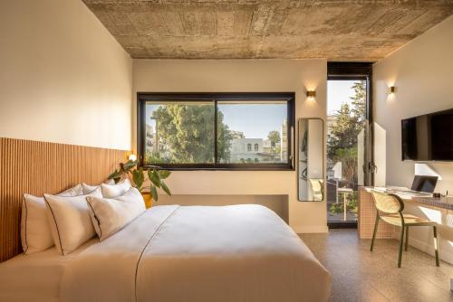 1 dormitorio con cama, escritorio y ventana en Savanna Dizengoff - Smart Hotel by Loginn Tel Aviv, en Tel Aviv