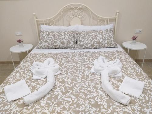 Una cama con toallas blancas y dos mesas. en Casetta Porta di Ligne, en Catania