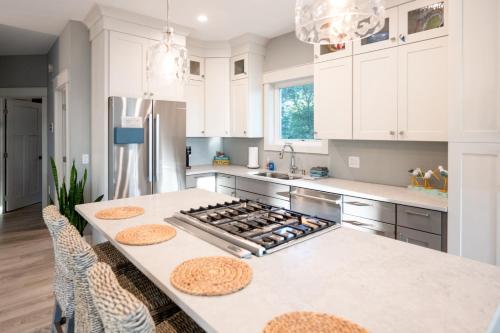 a kitchen with white cabinets and a kitchen island with a stove at Relax on Lake Michigan at Tranquil Shores in Norton Shores