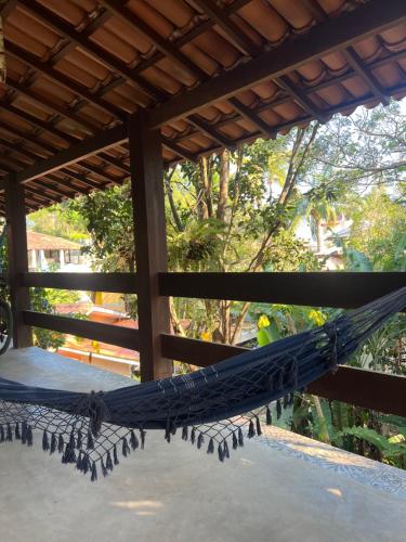 a hammock on a porch with trees in the background at Casa Espaçosa em Arraial D”Ajuda in Porto Seguro