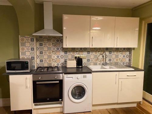 eine Küche mit einer Waschmaschine und einem Waschbecken in der Unterkunft The Windsor Room With Private Bathroom in Windsor