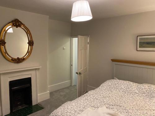 Schlafzimmer mit einem Bett und einem Wandspiegel in der Unterkunft The Windsor Room With Private Bathroom in Windsor