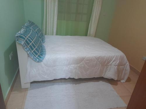 - un lit avec des draps blancs et un oreiller bleu dans l'établissement Pk cosy apartment, à Nairobi