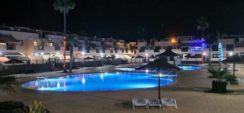 a swimming pool at night with two chairs and an umbrella at Los Geranios 21 Tenerife in Costa Del Silencio