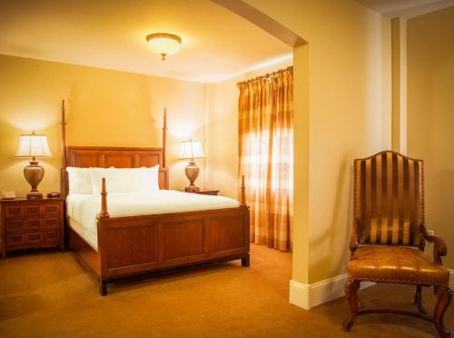 a bedroom with a bed and a chair at Grant Hall Hotel in Moose Jaw