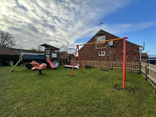 a playground in a yard with a house at The Chestnuts Holiday Cottages in Burgh le Marsh