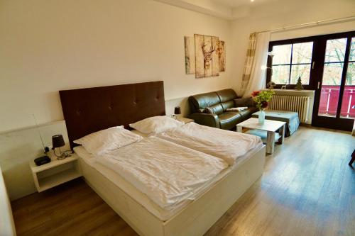 a bedroom with a bed and a chair and a couch at Hallelujah - Wunderschönes und gepflegtes Apartment mit Bademantelgang zur Therme in Bad Griesbach