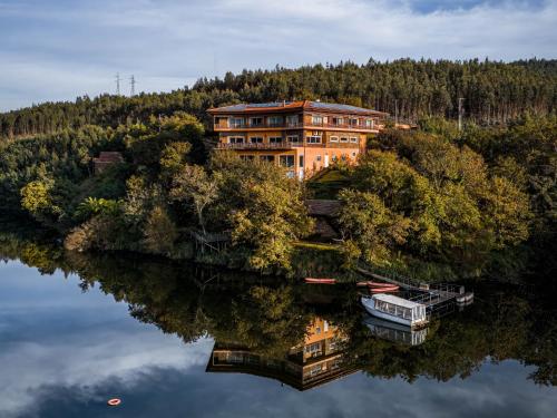 un gran edificio en una colina junto a un lago en Hotel Rural Quinta da Conchada, en Aguieira