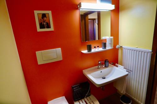 a bathroom with a sink and a red wall at Wunderschöne Ferienwohnung mit Bademantelzugang zur Therme im Golf- und Aktivitätsparadies Bad Griesbach in Bad Griesbach