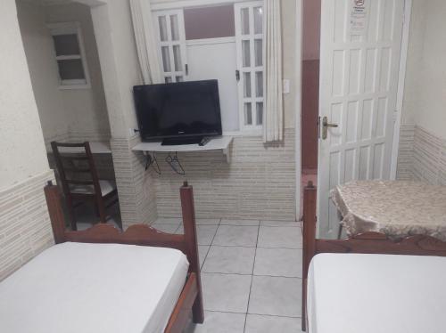 a room with two beds and a tv and a window at Pousada nascente do sol in Macaé