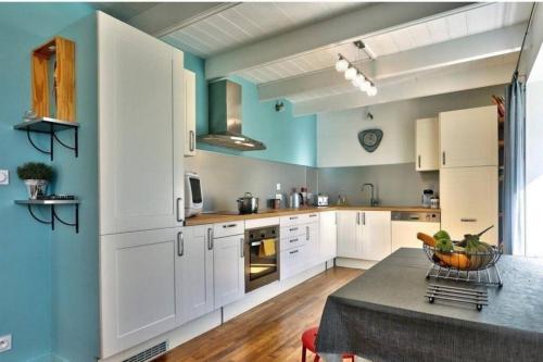 une cuisine avec des armoires blanches et une table dans l'établissement Maison avec Jardin,Terrasse,bar,baby foot 4-6 pers, au Guilvinec
