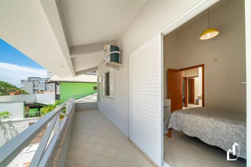 ein Schlafzimmer mit einem Bett und einem Balkon in der Unterkunft Casa com 05 dormitórios ideal as férias na praia in Canto Grande