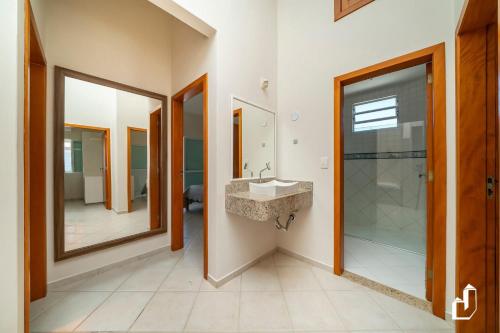 ein Badezimmer mit Waschbecken und Spiegel in der Unterkunft Casa com 05 dormitórios ideal as férias na praia in Canto Grande