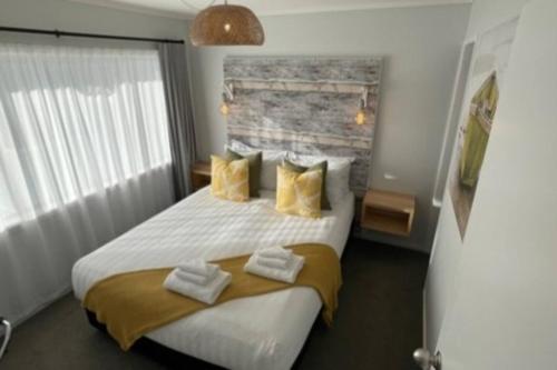1 dormitorio con 1 cama blanca grande con almohadas amarillas en Stay n Play n Russell, en Russell