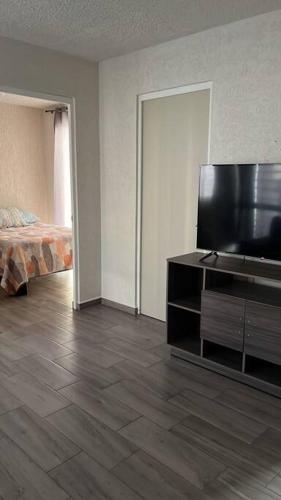 a living room with a flat screen tv and a bed at Depa Meraki More in Morelia