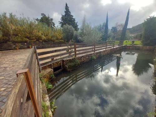 a bridge over a pond with clouds in the water at Carregã Water mill in Penela