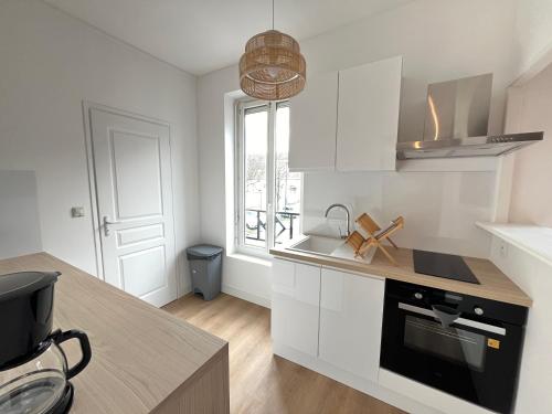 une cuisine avec des armoires blanches et un appareil noir dans l'établissement Le Pâtis - Proche Gare - Centre ville - 4 pers, au Mans