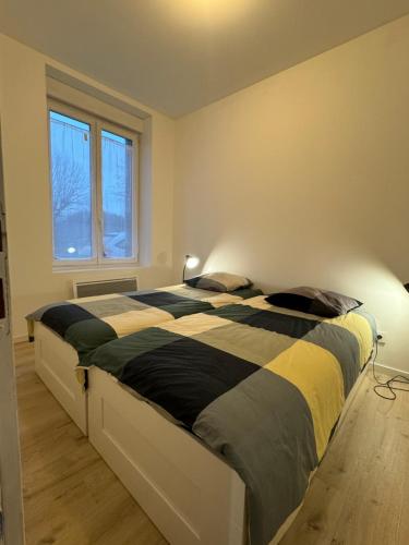 a bedroom with a bed with a black and yellow comforter at Eliya in Romilly-sur-Seine