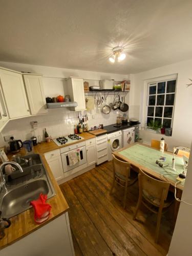 a kitchen with white cabinets and a wooden floor at Trendy 1BD Flat - 5 mins to Cambridge Heath! in London