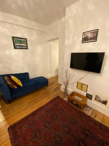 a living room with a blue couch and a flat screen tv at Trendy 1BD Flat - 5 mins to Cambridge Heath! in London