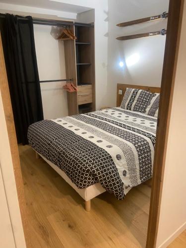 1 dormitorio con 1 cama con edredón blanco y negro en Charmant appartement en Saint-Claude
