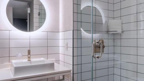La salle de bains blanche est pourvue d'un lavabo et d'un miroir. dans l'établissement Roomza Times Square at Pestana CR7, à New York