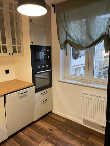 a kitchen with white cabinets and a black appliance at Przystań Północy in Suwałki