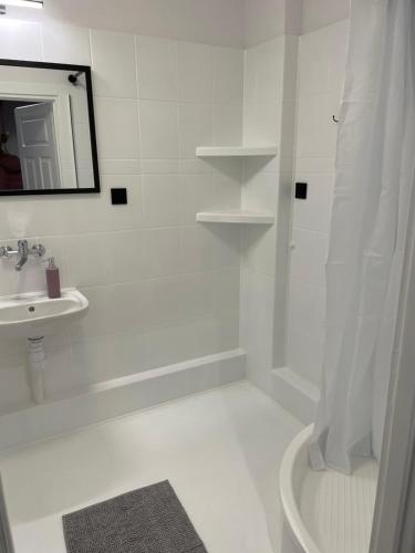 biała łazienka z umywalką i prysznicem w obiekcie Przystań Północy w mieście Suwałki
