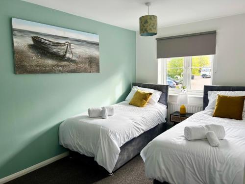 two beds in a room with a painting on the wall at Ripon House in Dallington