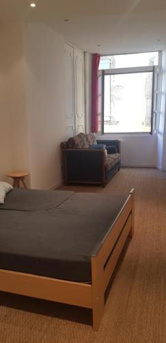 une chambre avec un lit, un canapé et une fenêtre dans l'établissement Centre ville le Puy-en-Velay au 1er étage, au Puy-en-Velay