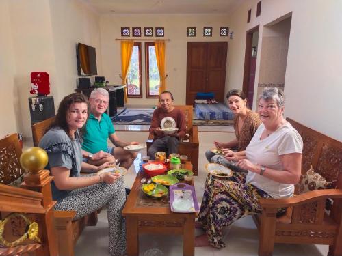 Wildan Homestay في Mangun: مجموعة من الناس يجلسون حول طاولة يأكلون الطعام