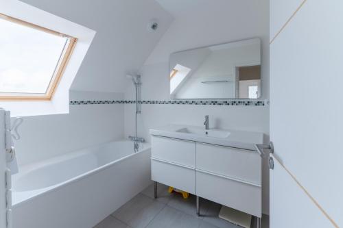 a white bathroom with a sink and a mirror at TY KREIZH - Maison neuve avec piscine proche mer in Saint-Pabu